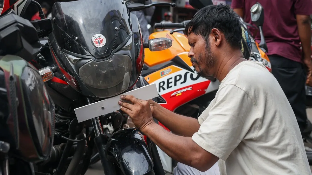 মোটরসাইকেলের সামনে নাম্বার প্লেট বসানোর জন্য সাদা বোর্ড স্থাপন করা হচ্ছে