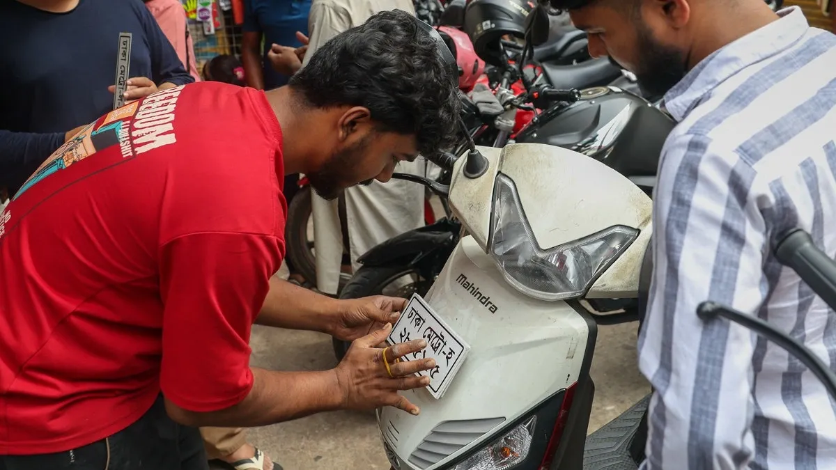 নির্ধারিত মাপ অনুযায়ী স্কুটির সামনে নাম্বার প্লেট বসানো হচ্ছে