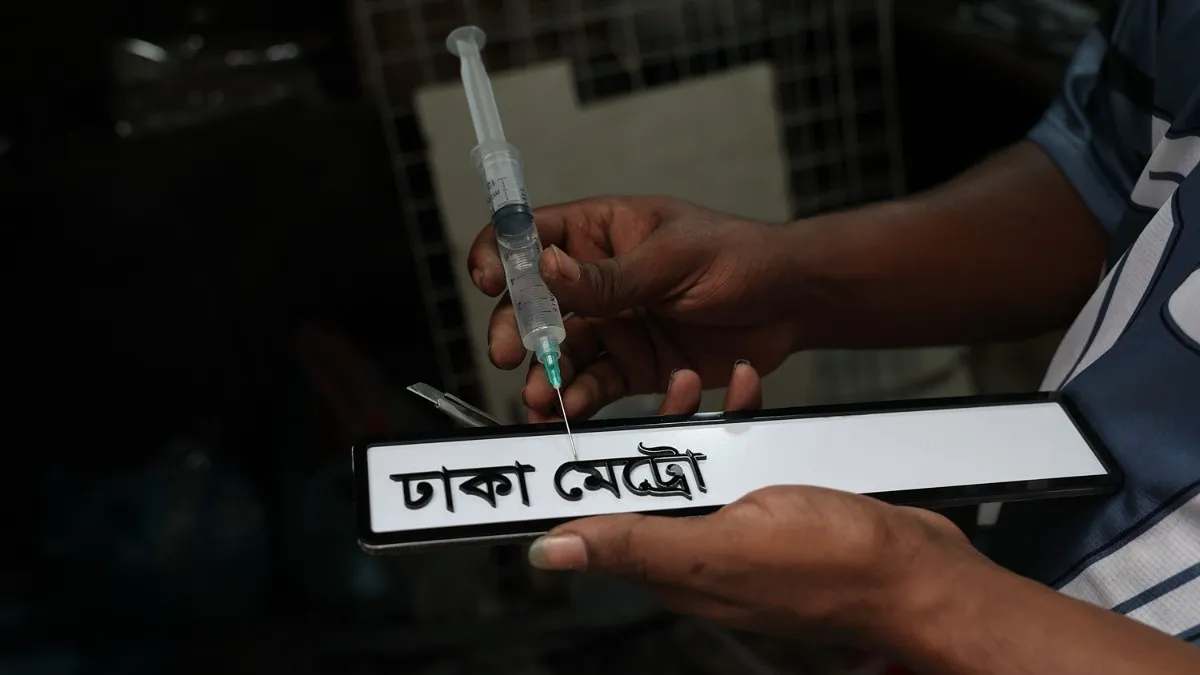 আঠা দিয়ে নাম্বার প্লেটের অক্ষর ও সংখ্যা বসানো হচ্ছে