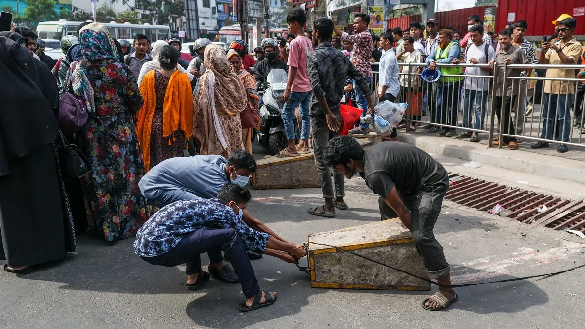 সড়ক অবরোধের জন্য রোড ব্যারিকেড টেনে নিয়ে যাচ্ছেন আন্দোলনরত শ্রমিকরা